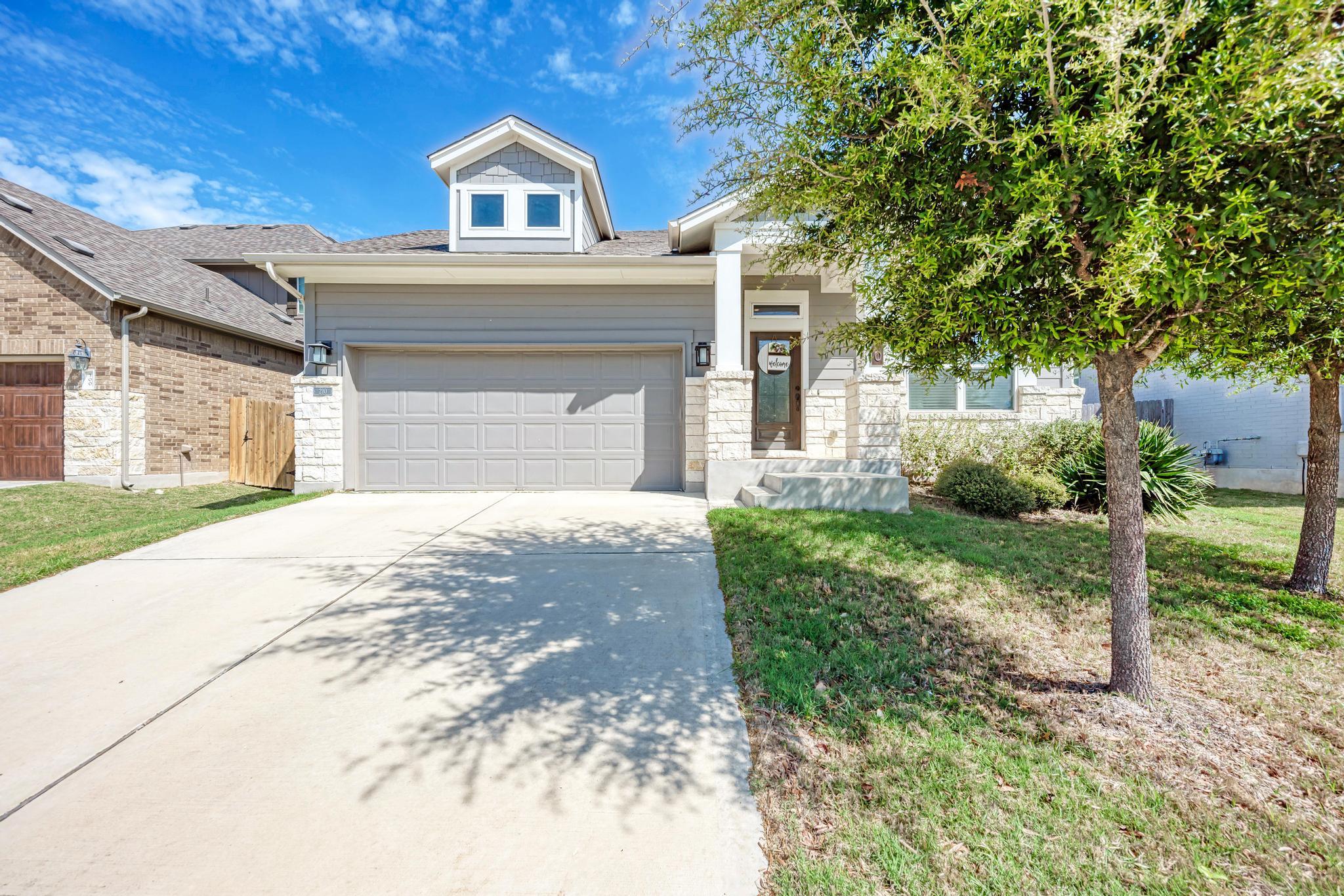 Craftsman-style home under a wide blue Texas sky in the Carmel Creek neighborhood of Hutto